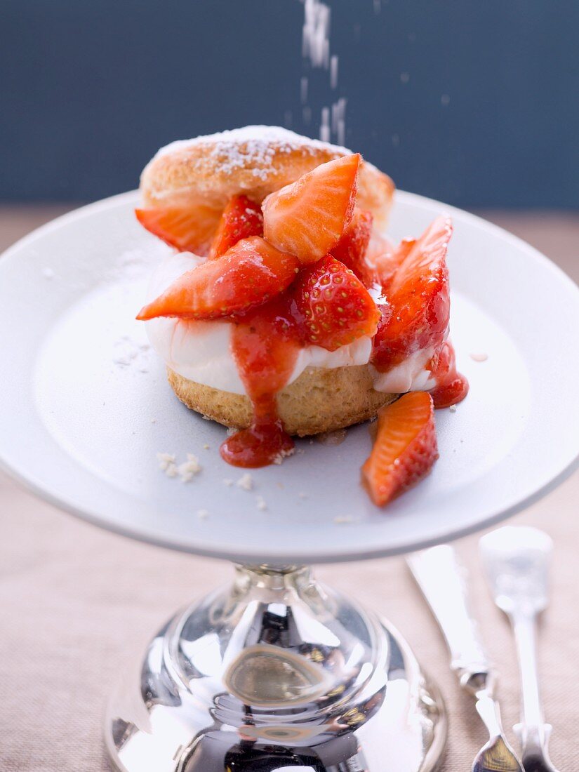 A scone topped with cream and strawberries