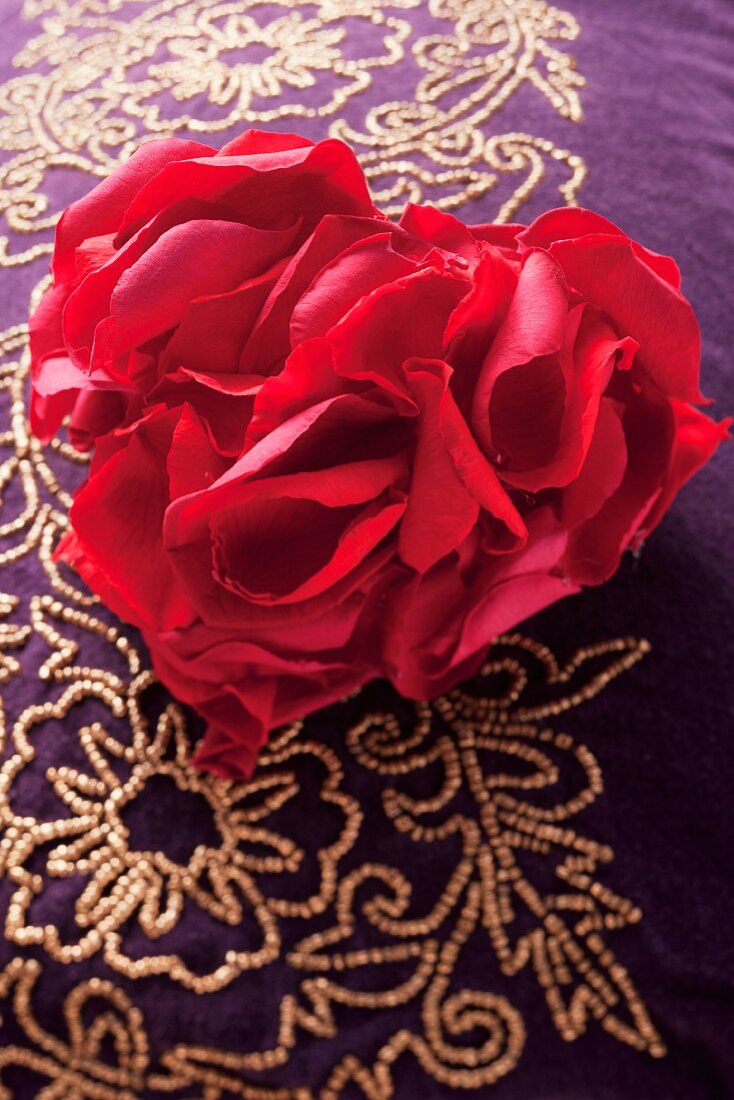 Rosenblütenblätter in Herzform auf perlenbesticktem Kissen