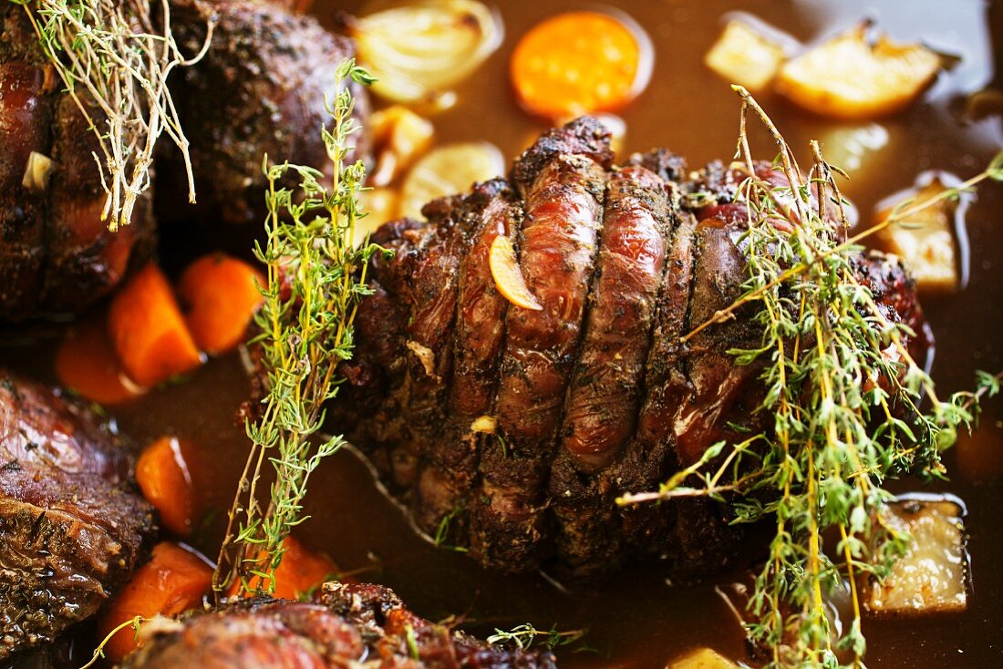 Roast venison with root vegetables and thyme in a pan