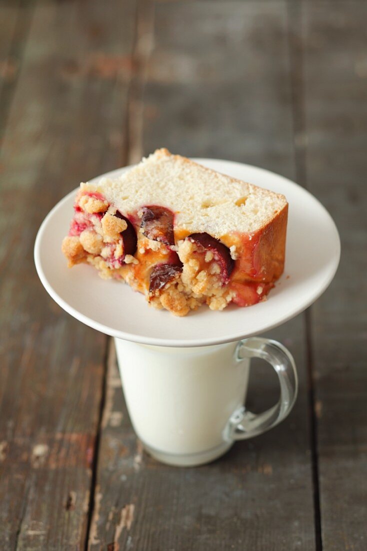 Ein Stück Pflaumen-Streusel-Kuchen auf Milchglas