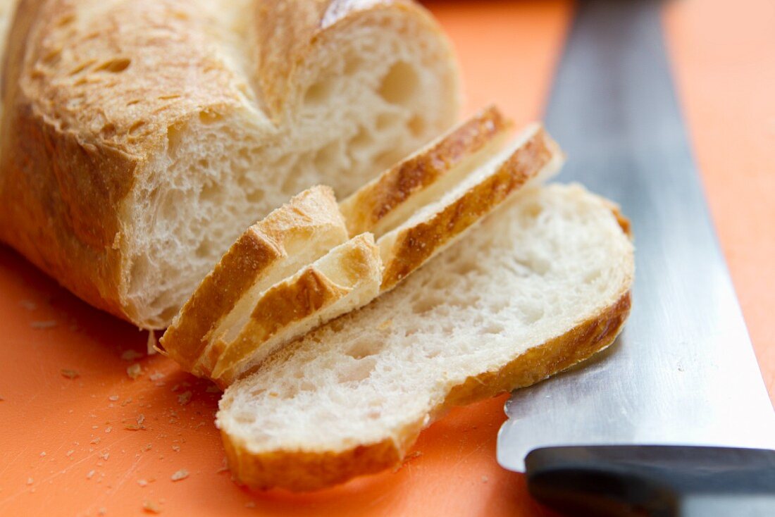 Slices of baguette with a knife on a bread board