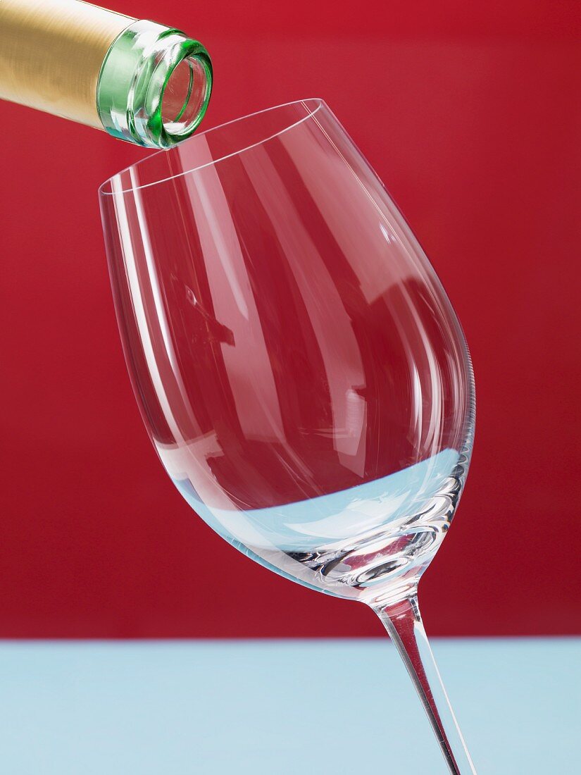Wine being poured into a white whine glass