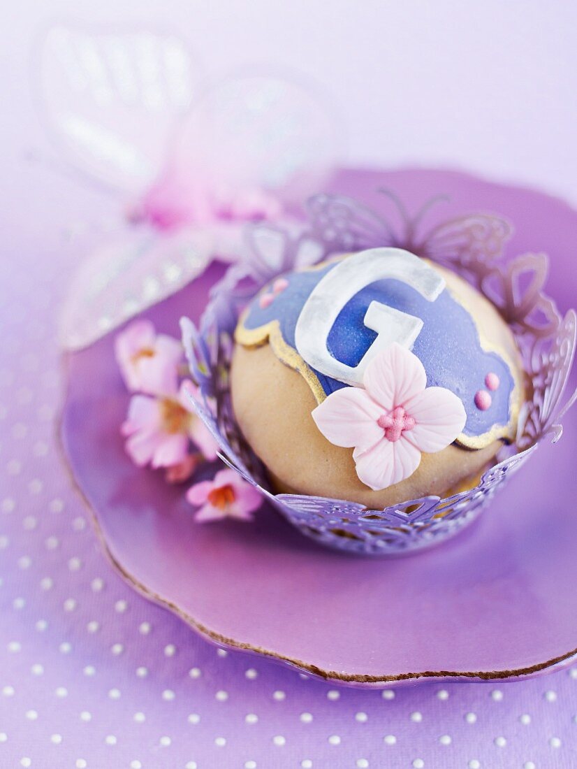 A cupcake with purple decoration on a purple plate