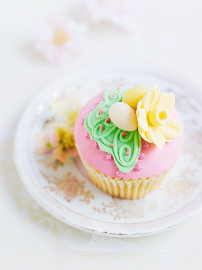 A cupcake decorated with pick frosting and marzipan decorations