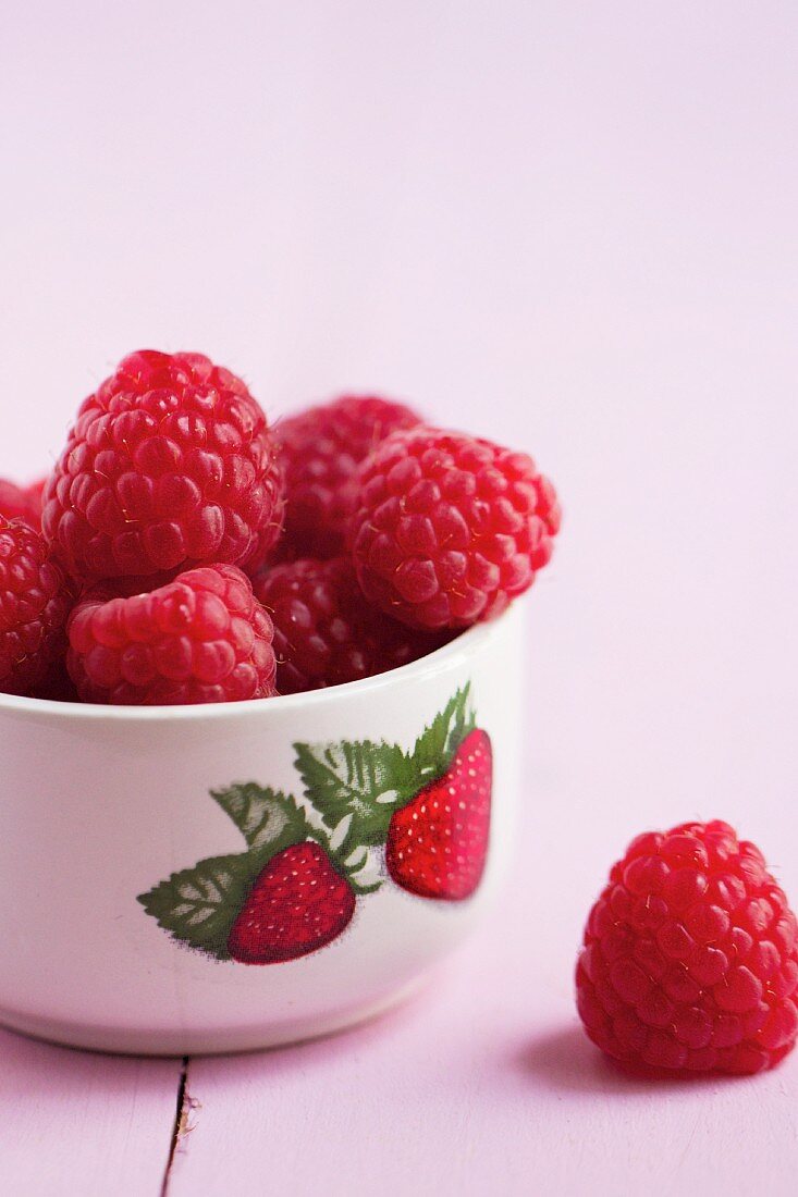 Fresh raspberries in a bowl with a strawberry picture