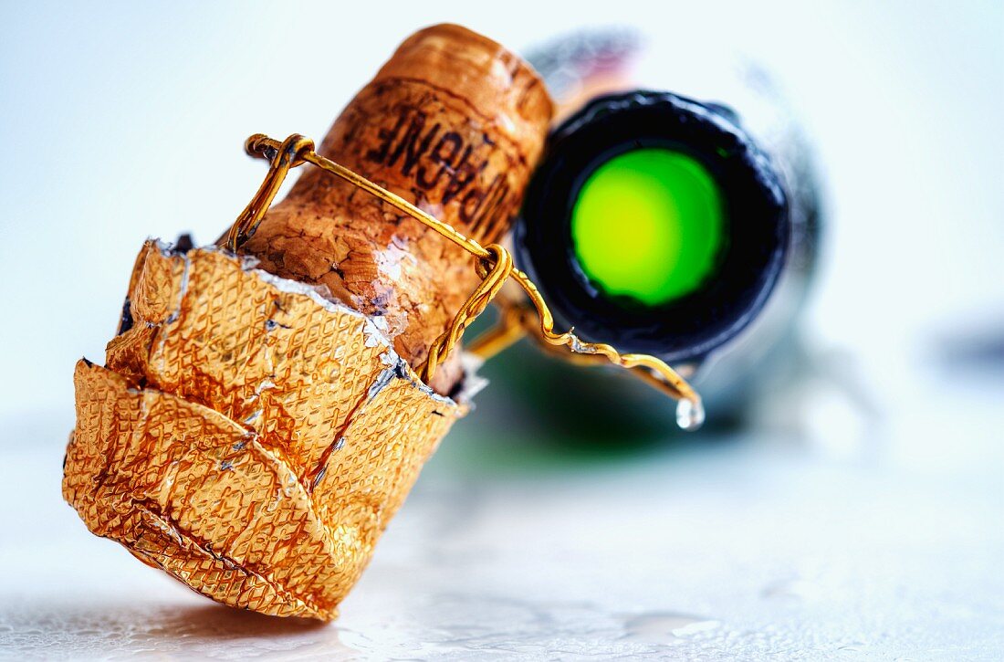 A champagne cork and an open bottle of champagne