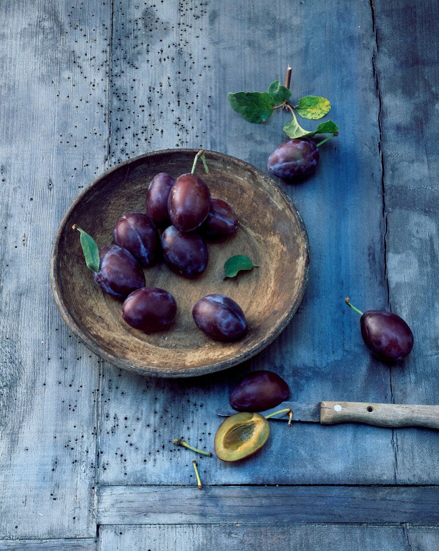 Plums in a wooden bowl and knifes
