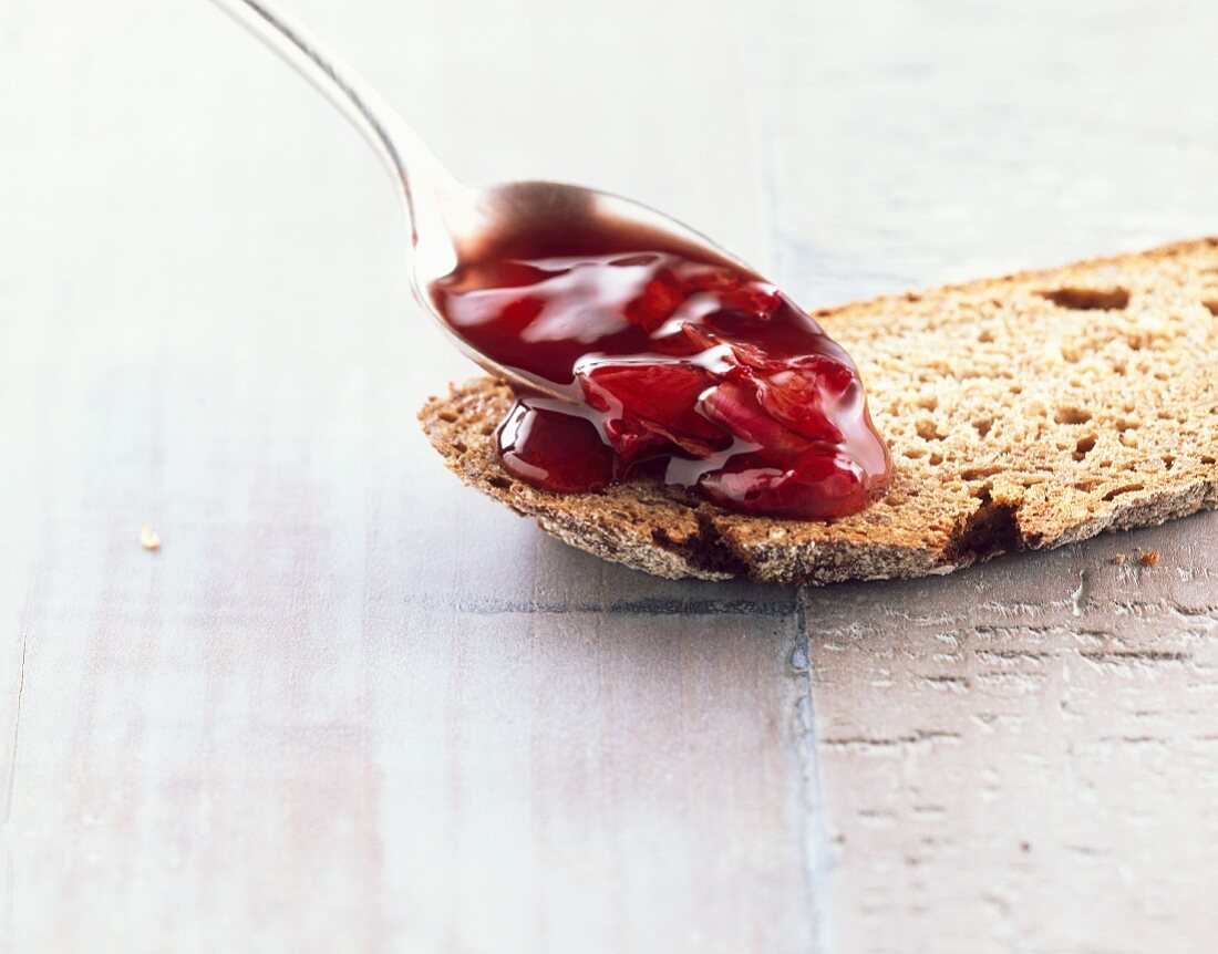 Rosenblütenkonfitüre auf Löffel und Brot