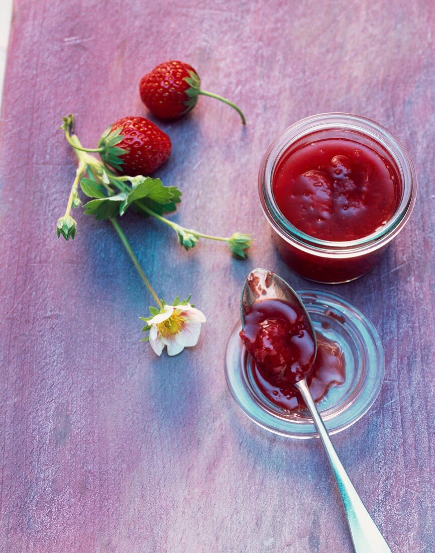 Strawberry and rose jam on a spoon and in a jar