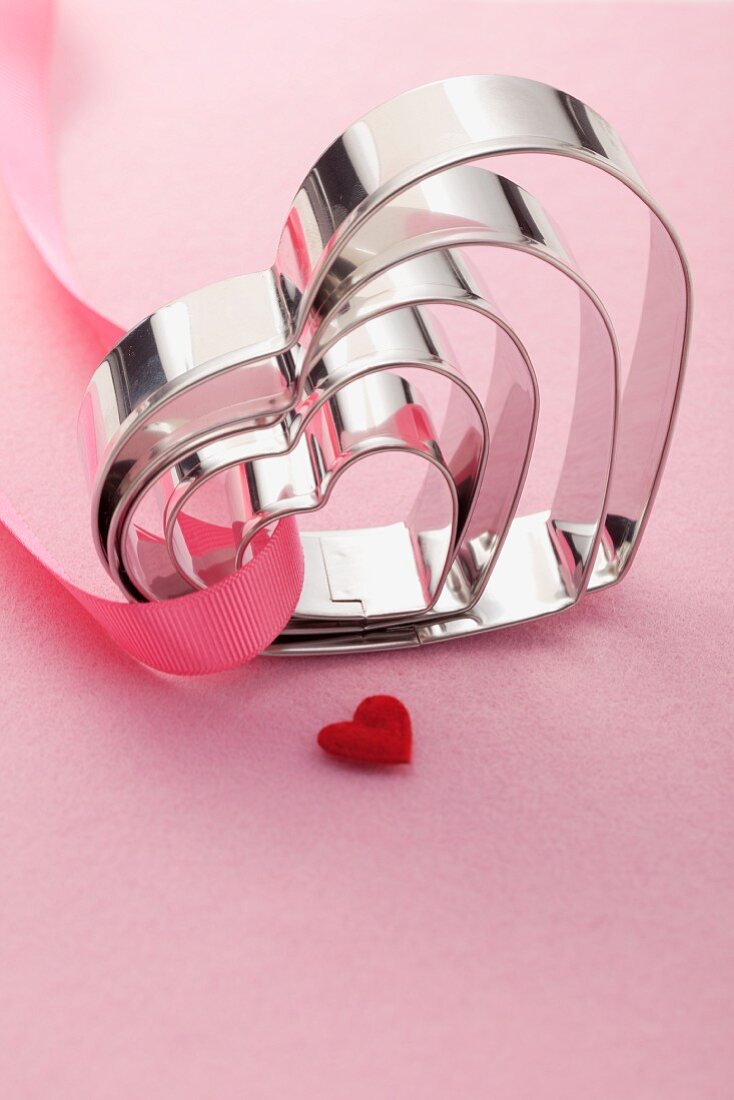 Heart-shaped baking tins on a pink surface