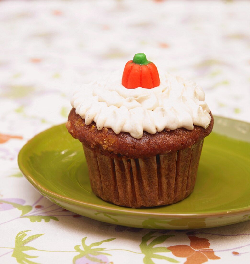 A Pumpkin Spice Cupcake with a Pumpkin Candy on a Green Plate