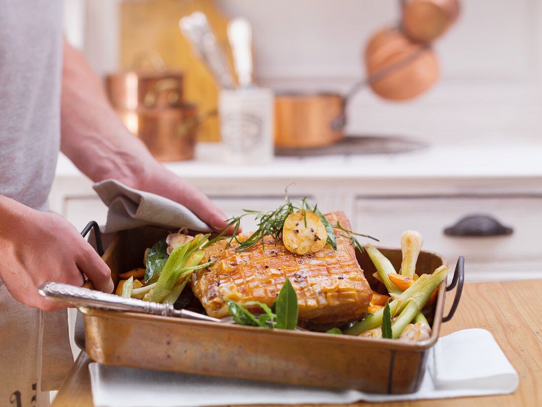 Roast pork with vegetables in a roasting tin