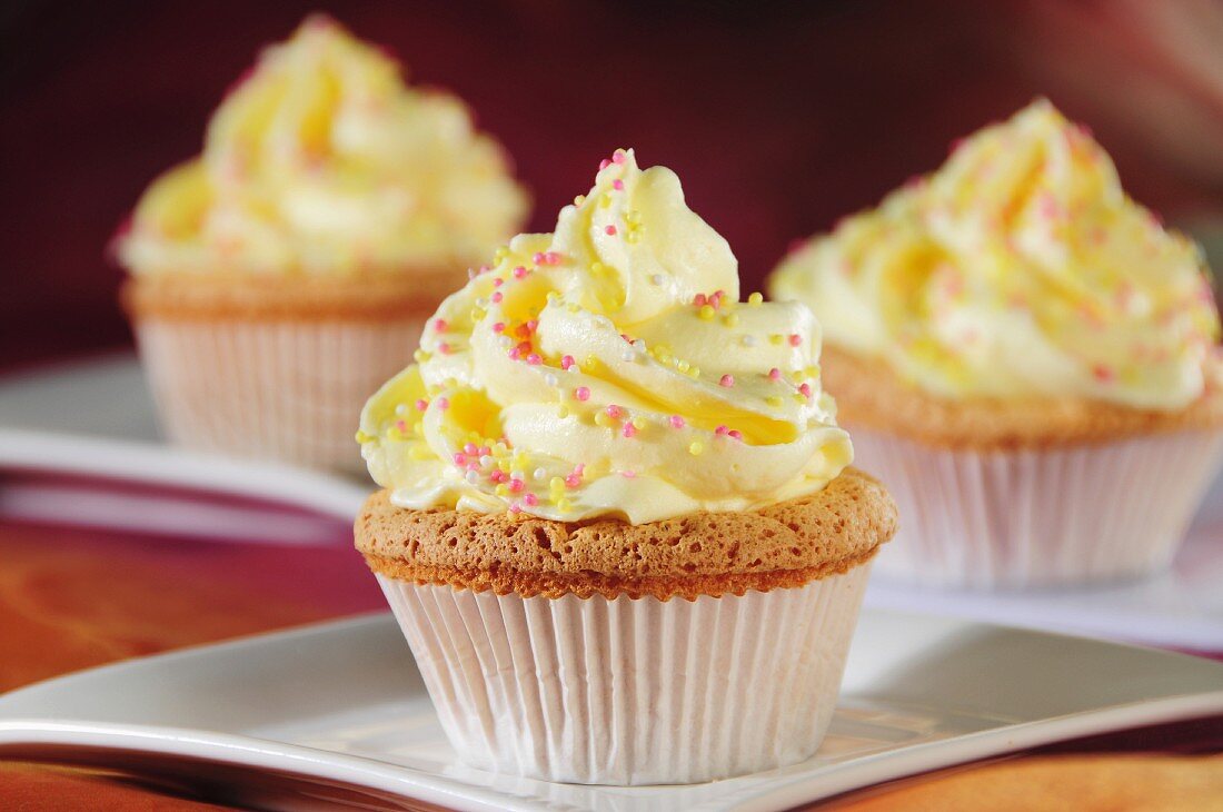 Cupcakes mit gelber Creme und Zuckerstreuseln