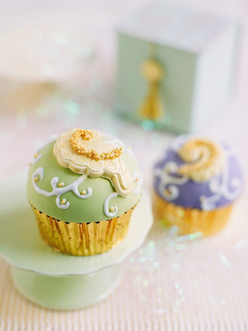 Festlich verzierte Cupcakes mit grünem und mit lila Fondant
