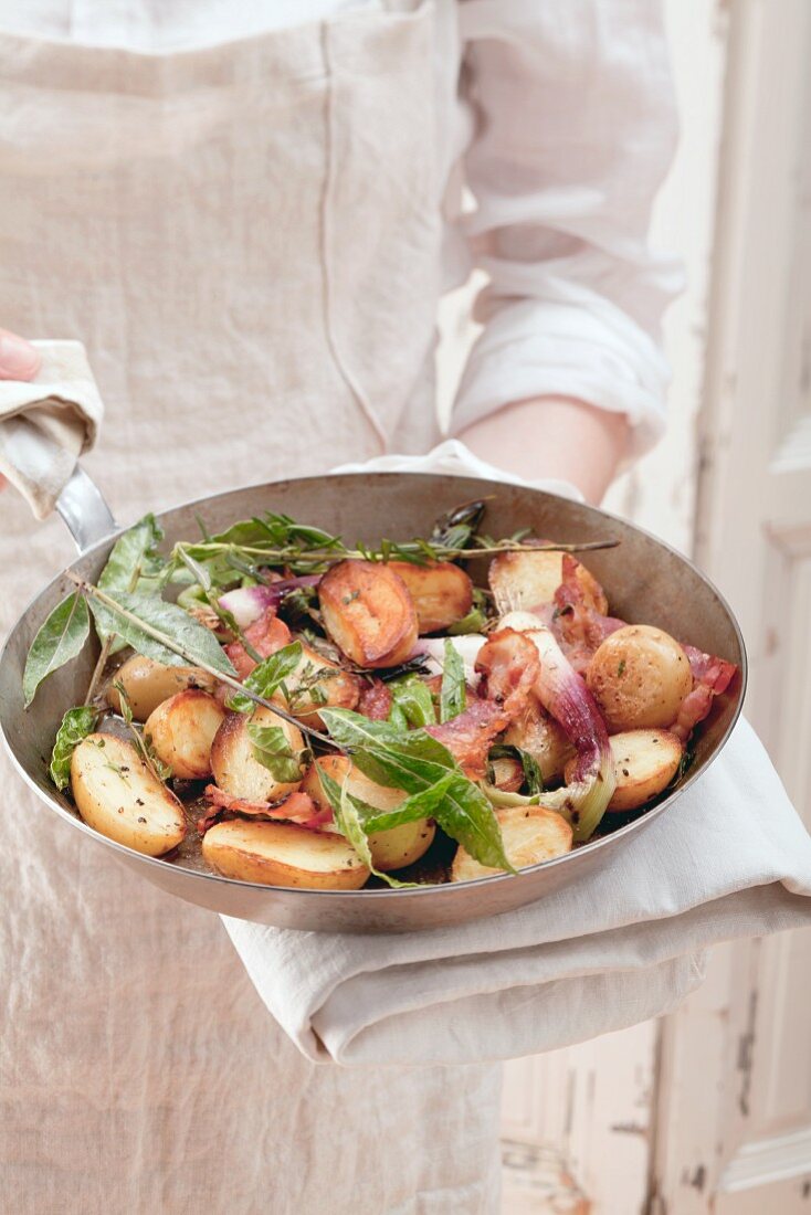 Potatoes and spring onions with herbs in a pan