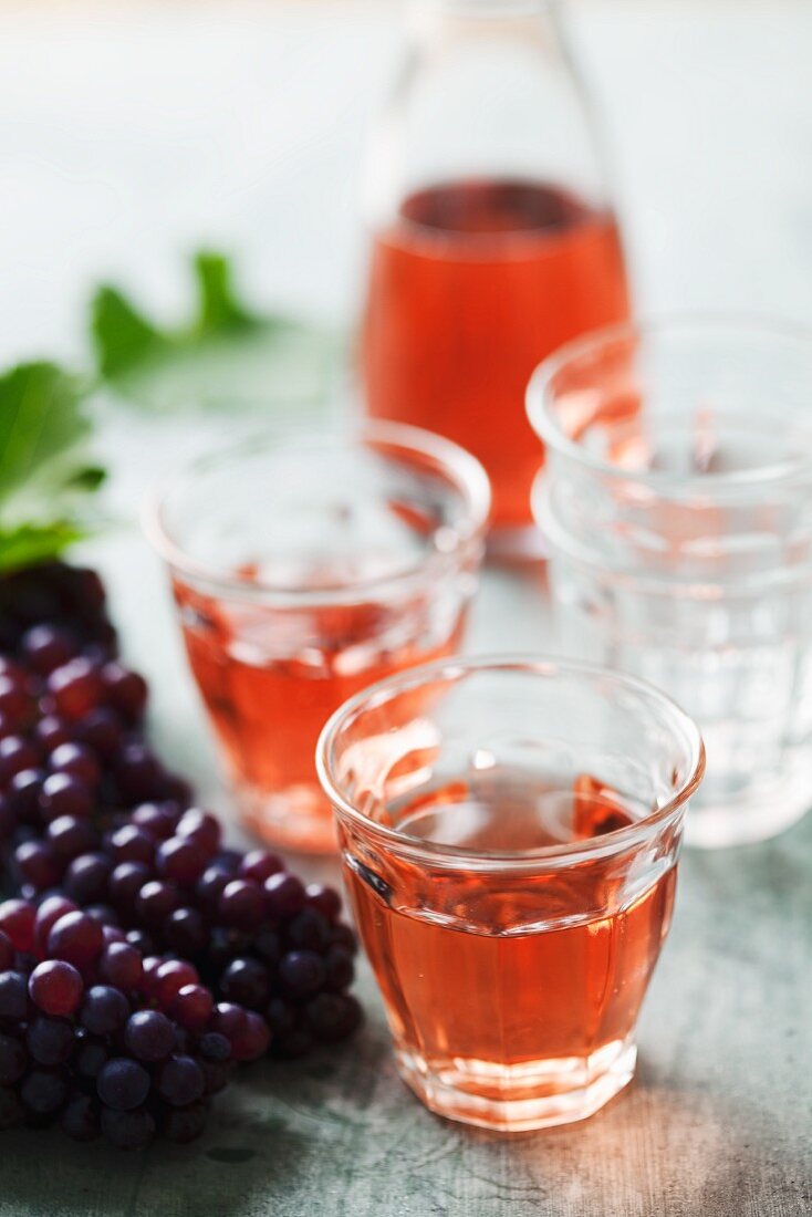 Two glasses of rose wine with a bunch of grapes