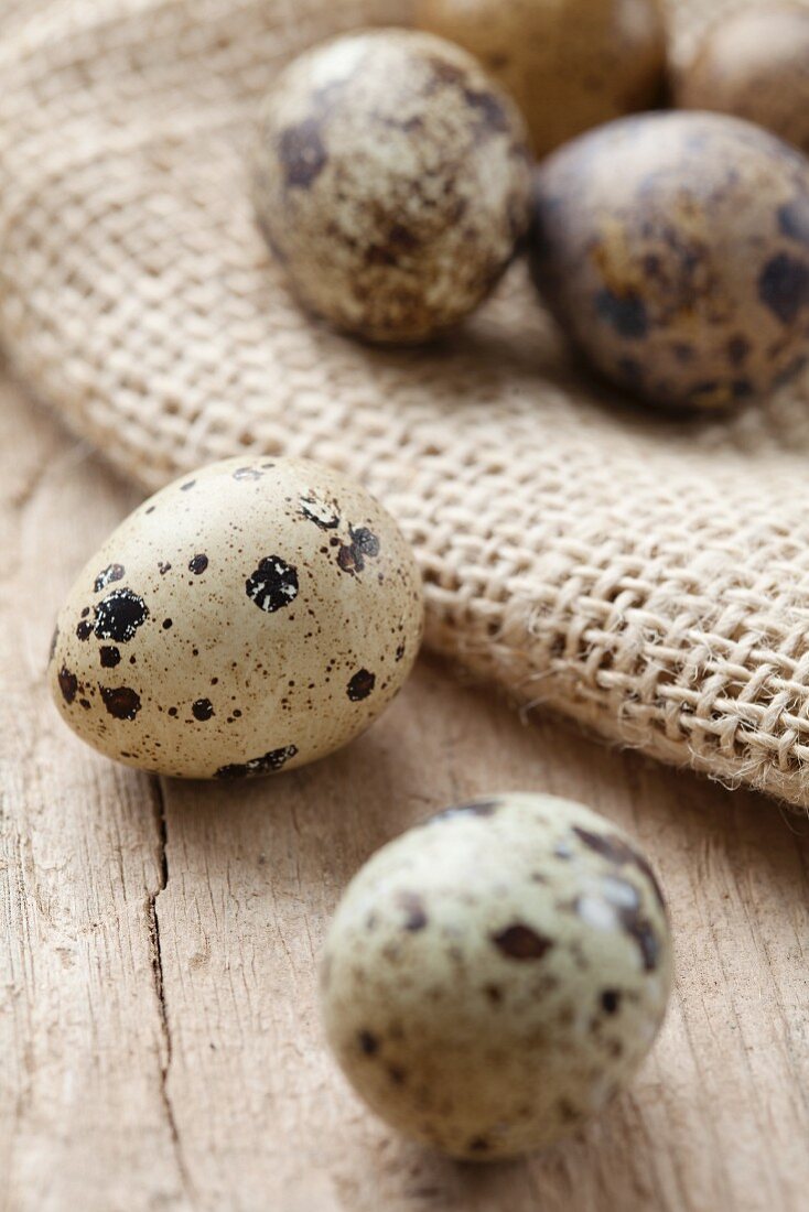 Quail's eggs on a wooden surface and on a jute sack
