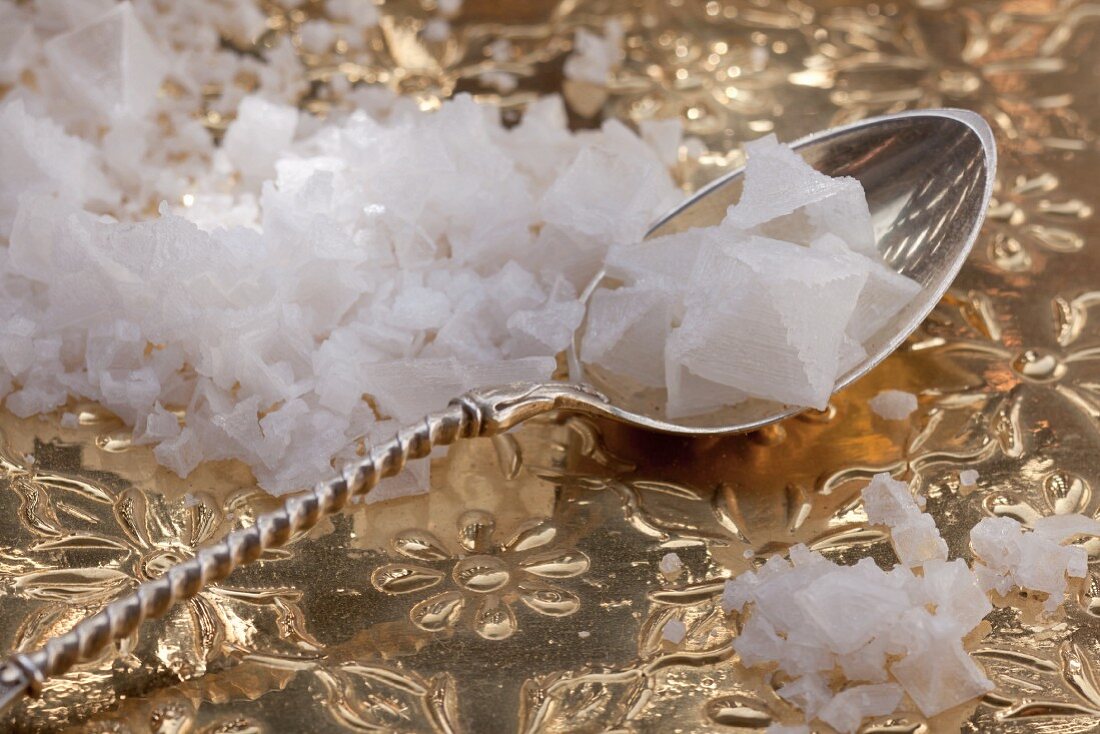 Salt crystals on a silver spoon and on a golden surface