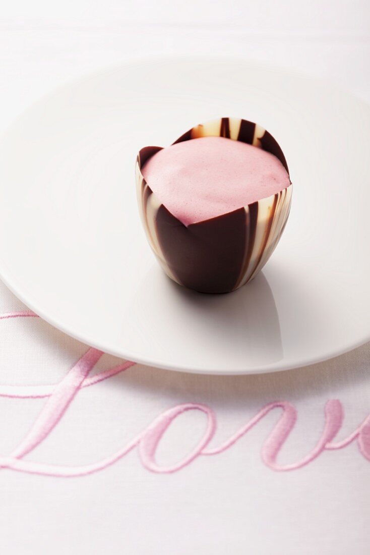 A pink praline on a cloth embroidered with the word 'Love'