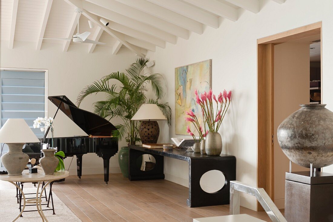 Musikzimmer mit schwarzem, geöffneten Konzertflügel; an der Wand ein schwarzes Sideboard mit pinkfarbenen Blumen in drei Vasen