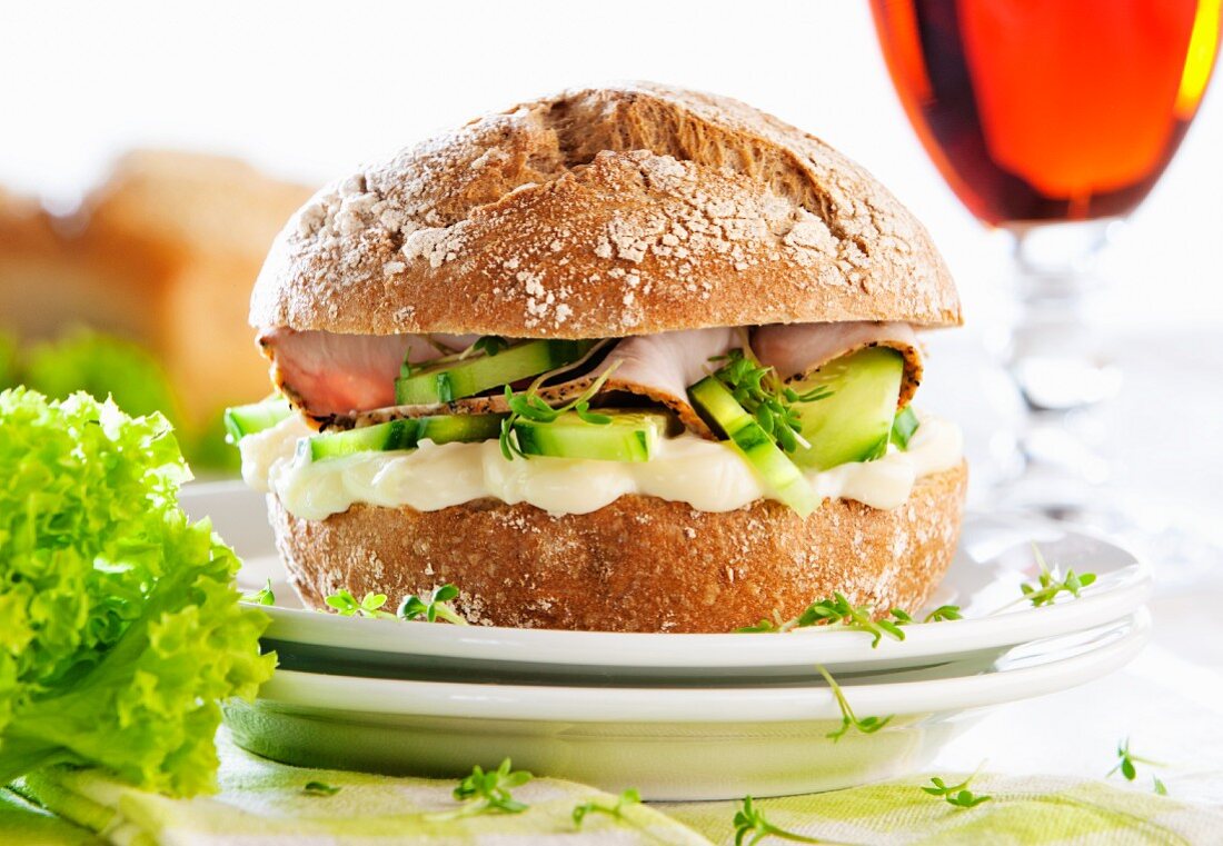 A rye bread roll with cream cheese, cucumber, turkey breast and cress