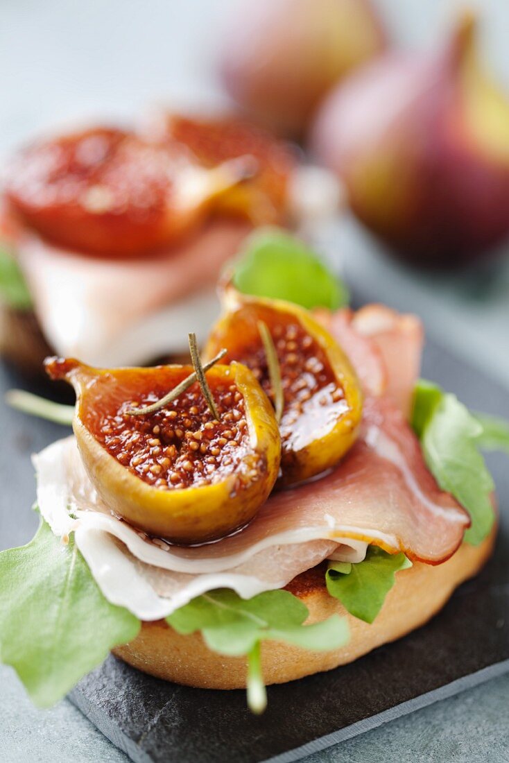 Crostini topped with rocket, raw ham, oven-baked balsamic figs and rosemary