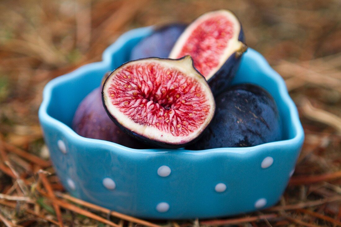 Fresh figs, whole and halved, in a heart-shaped bowl