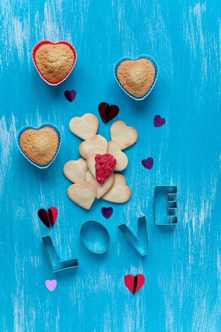Herzförmige Kekse, Vanille-Muffins und Schriftzug LOVE aus kleinen Keksausstechern