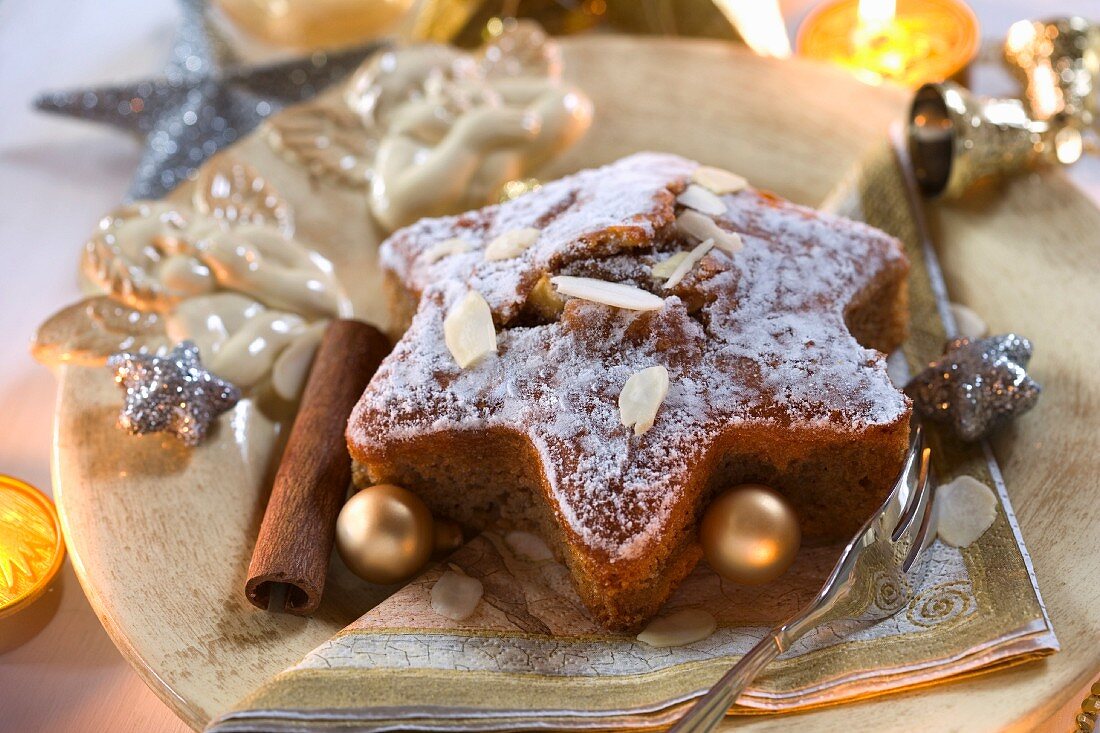 A star-shaped spiced cake with almonds and Christmas baubles on a Christmas angel plate