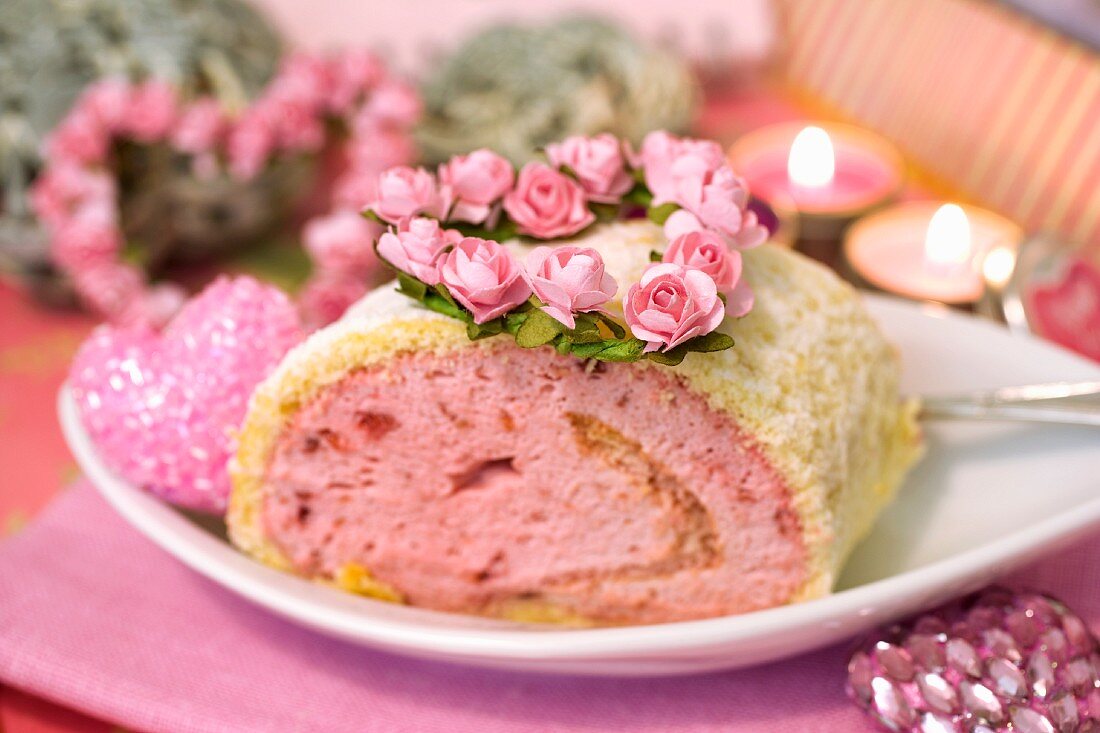 Himbeer-Erdbeer-Biskuitrolle mit Rosendekoration zum Valentinstag