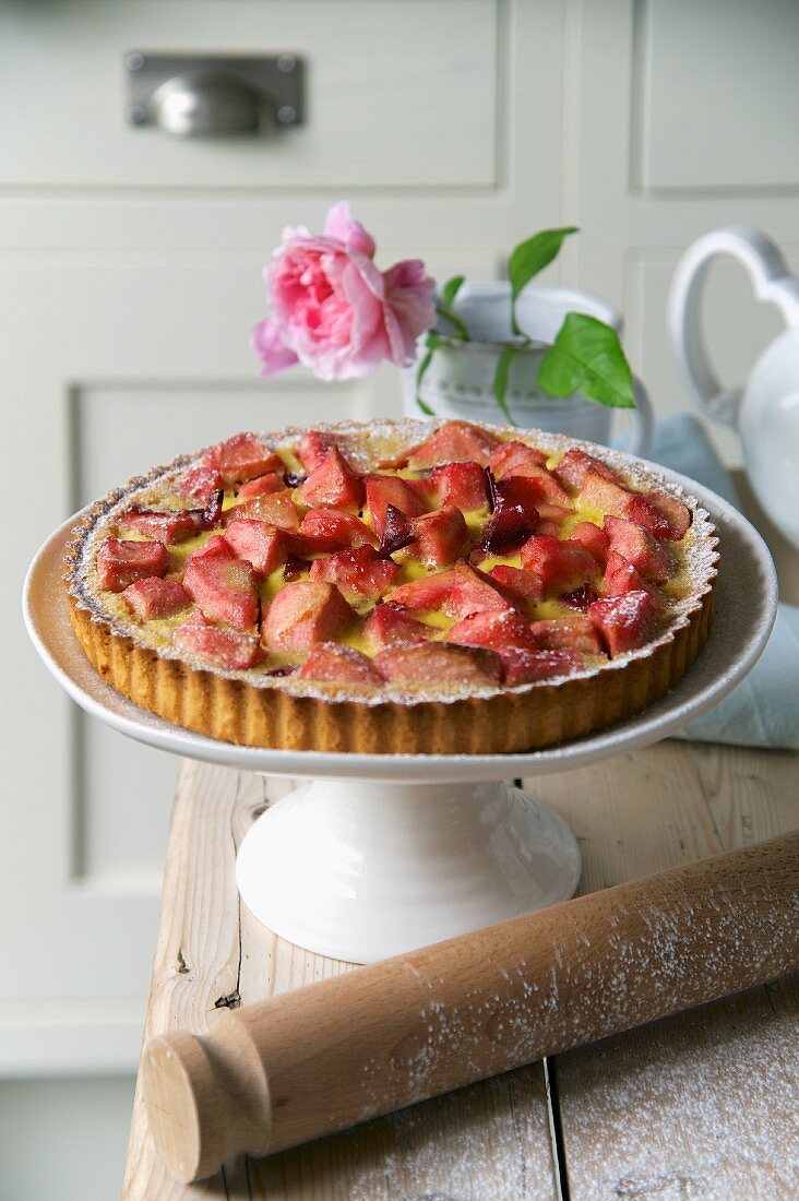 Plum and apple tart on a cake stand