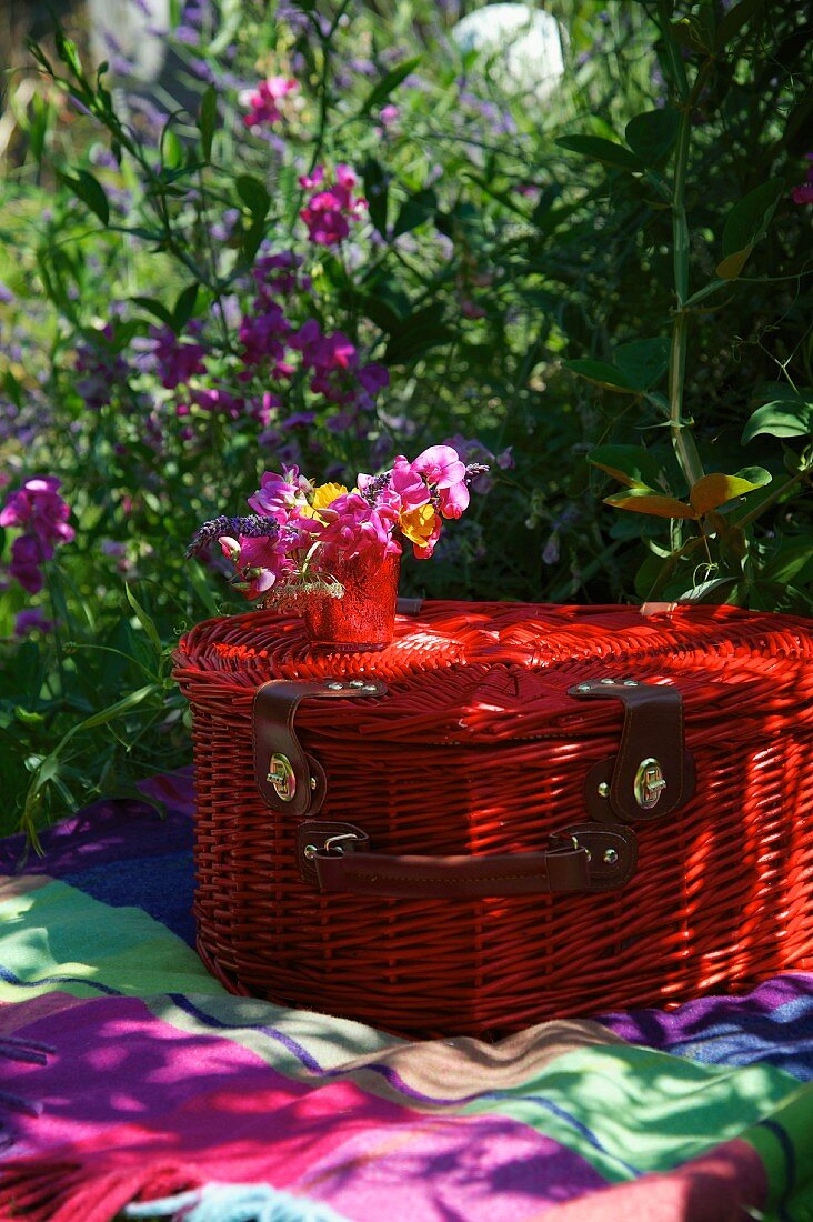 Roter Picknickkorb auf einer Decke im Garten