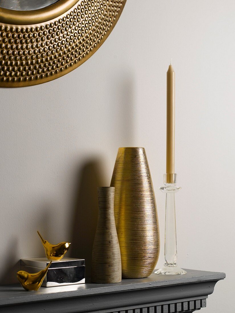 Vases and candlesticks on shelf below mirror