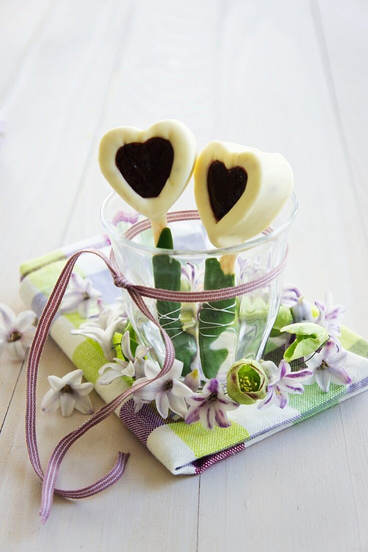 Herzen aus weisser Schokolade und Marmelade im Glas mit Frühlingskränzchen