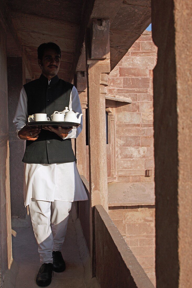 Indian waiter serving tea in Raas Haveli Hotel, Jodhpur, India