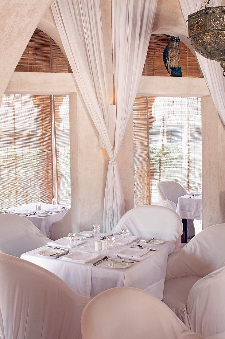 Elegant restaurant interior with white chairs and curtains in Raas Haveli Hotel, Jodhpur, India