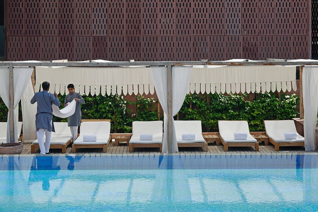 Hotel staff working next to luxurious swimming pool in Raas Haveli Hotel, Jodhpur, India