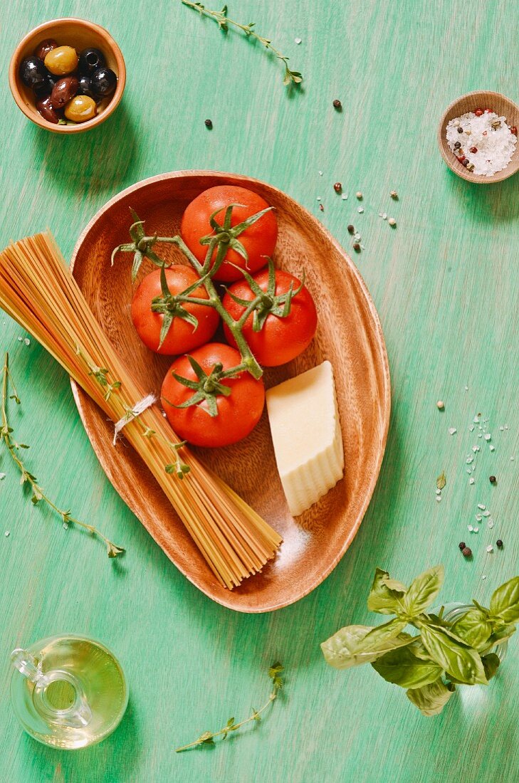 Stillleben mit Tomaten, Nudeln, Käse, Basilikum, Gewürzen und Oliven