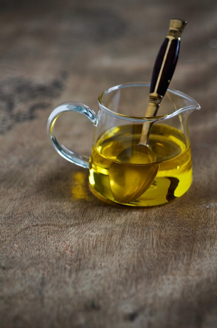 Olive oil in a glass jug with a spoon