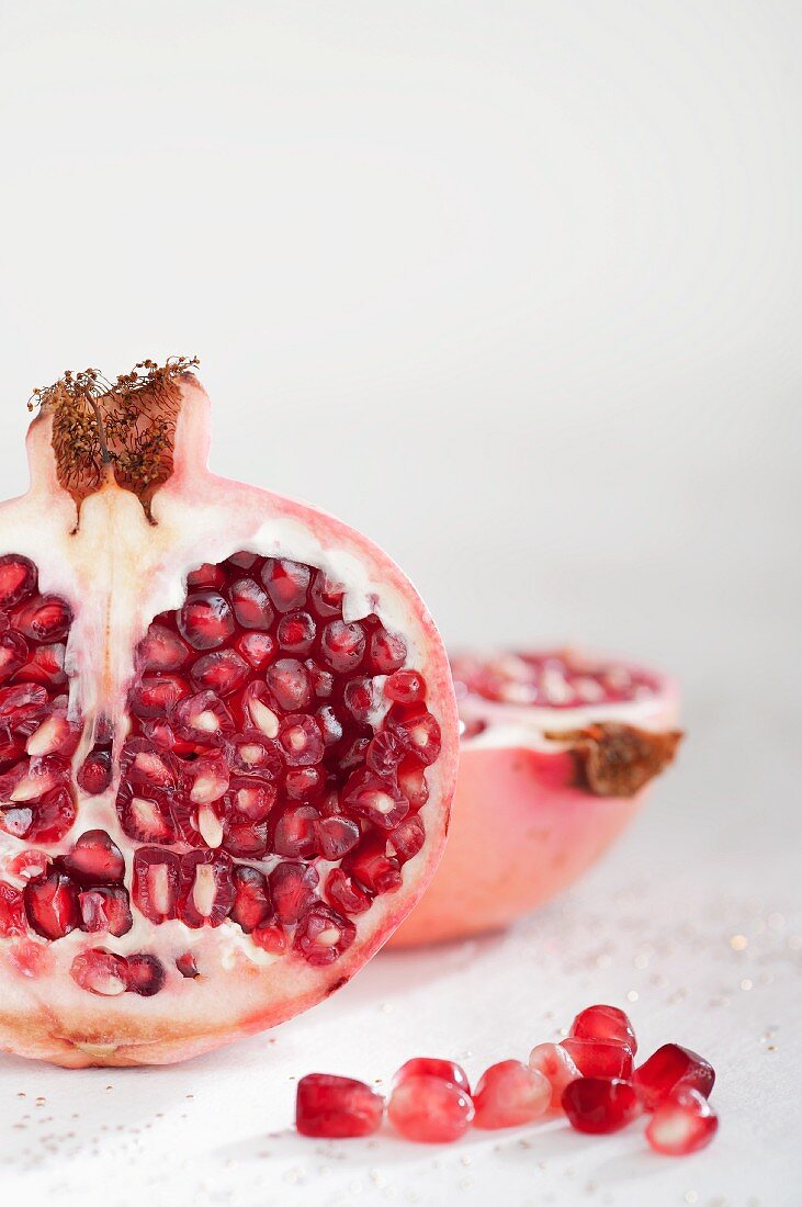 A pomegranate, halved and pomegranate seeds
