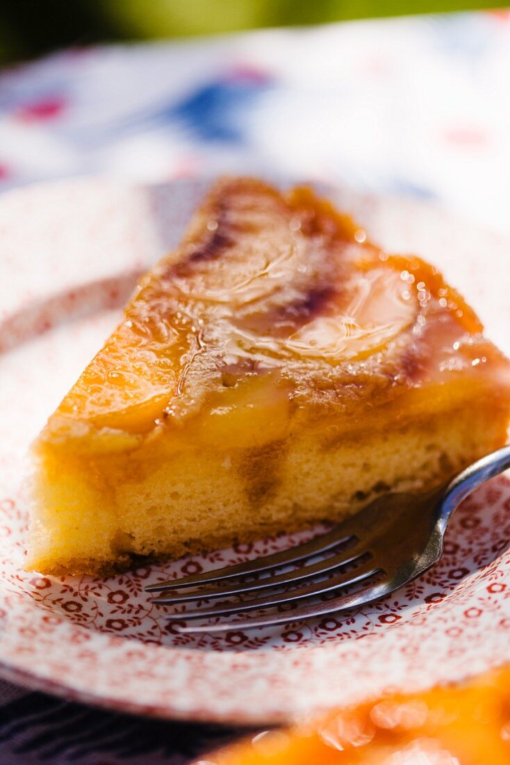 A Slice of Peach Upside Down Cake on a Plate; On a Sunny Outdoor Table