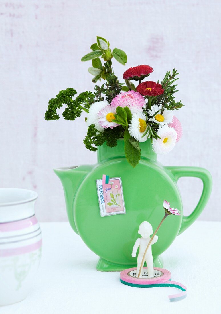 Posy of bellis and herbs in green retro jug