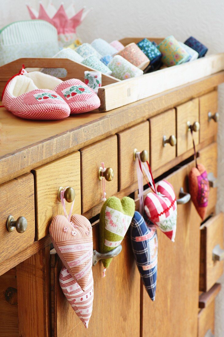 Shop counter with scented sachets hanging from handles; slippers, toiletry bags and rolls of ribbon on counter