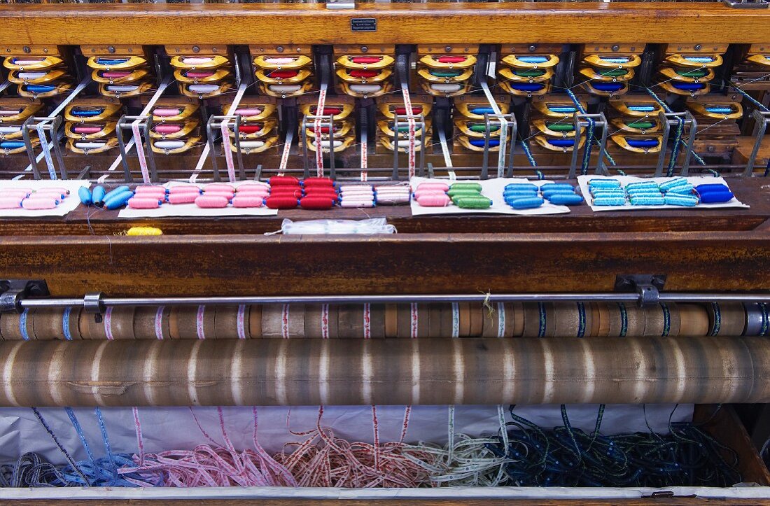 View of old Jacquard loom with finished ribbons emerging from bottom