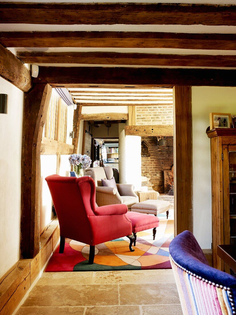 Rustic foyer with open doorway and view of red reading chair in country house with exposed wooden structure