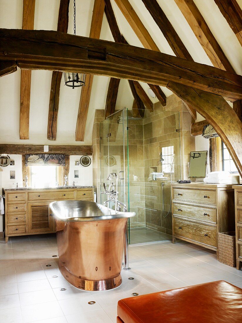 Free-standing, vintage copper bathtub in modern bathroom in rustic setting