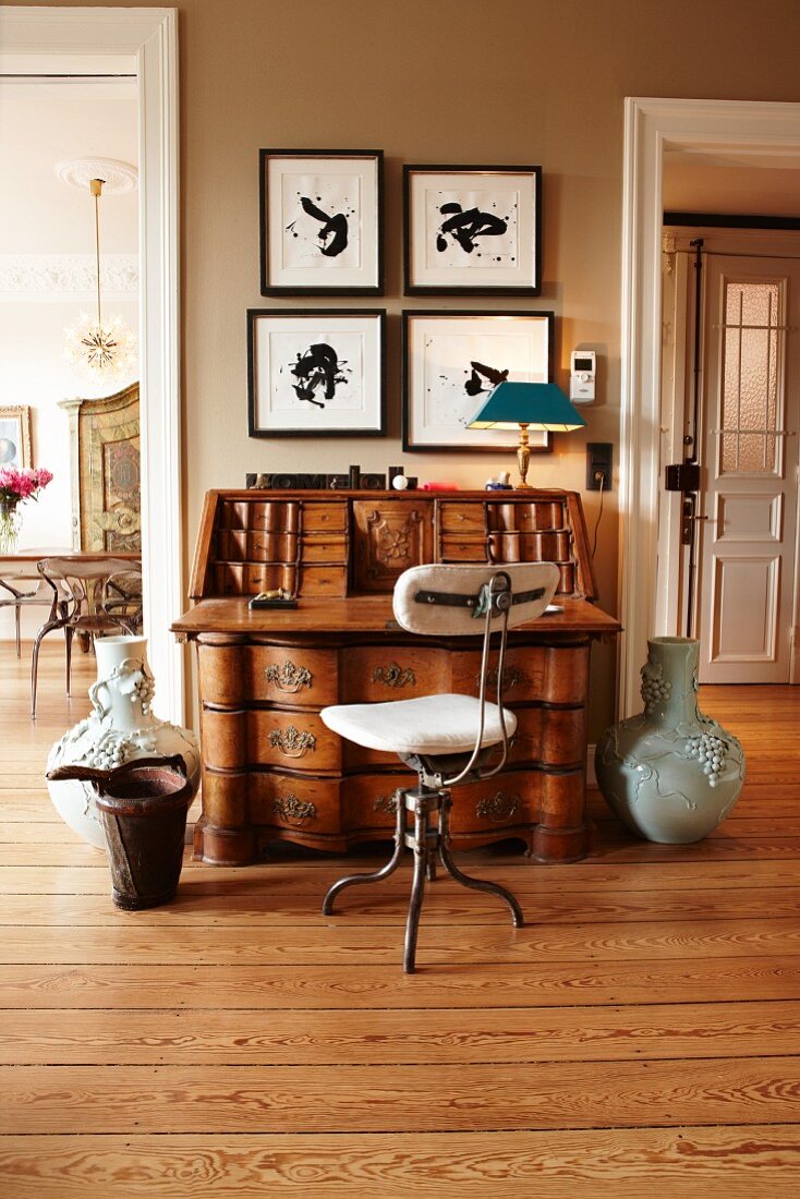 Antique bureau and retro chair against wall between two doorways in renovated, period building
