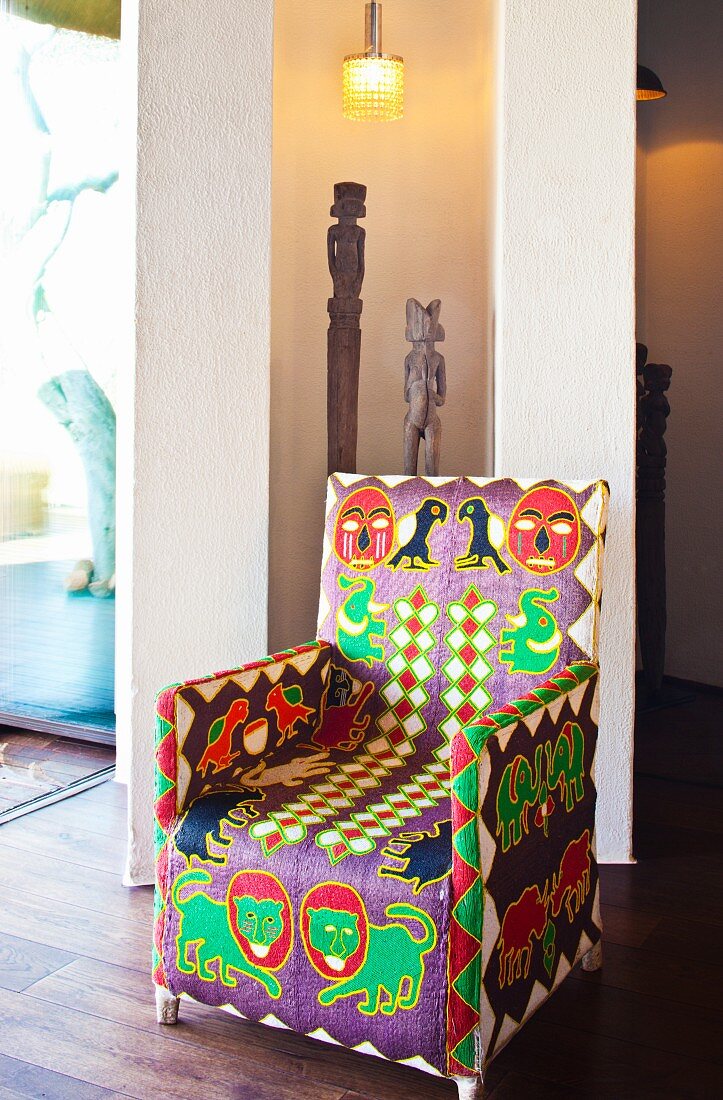 Ethnic-style armchair in front of African wooden figures