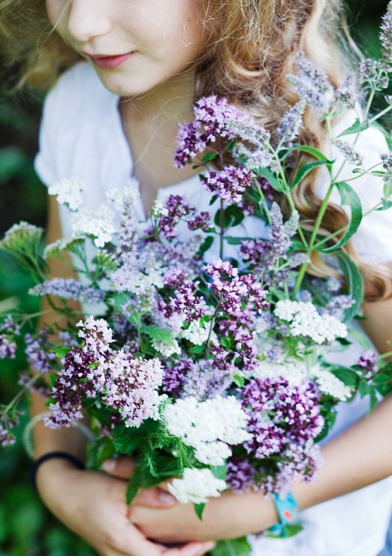 Girl holding bouquet of fragrant herbs in garden