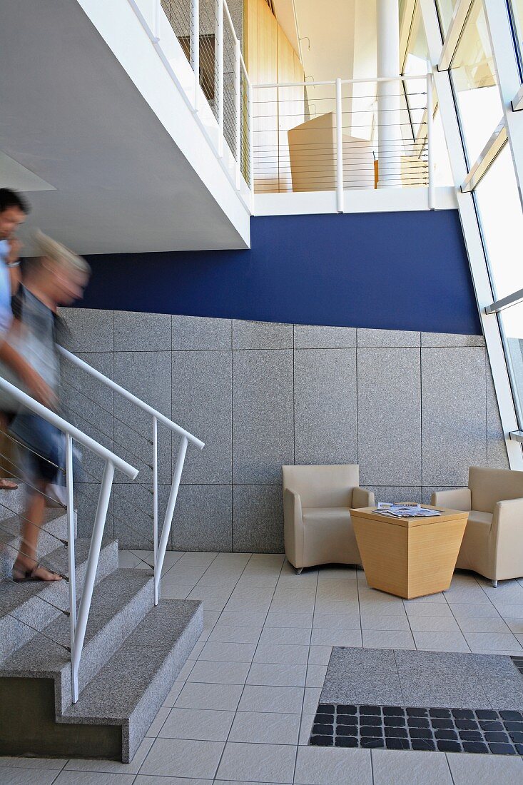 People on steps in open-plan foyer with lounge furniture